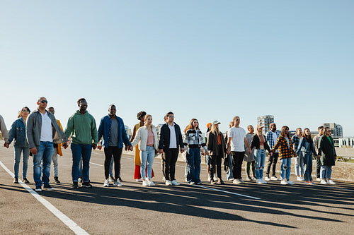 Group of people holding hands in solidarity on an open road