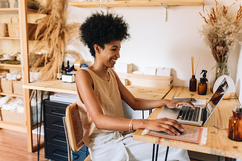 Woman jewelry business owner using laptop in workshop