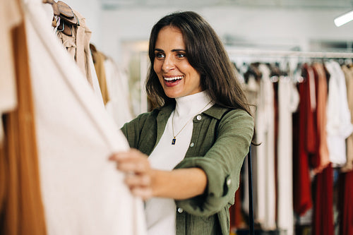 Woman getting excited while shopping for clothing in a fashionable boutique