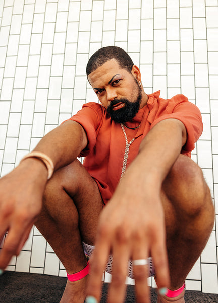 Non-conforming young man wearing drag against a white background