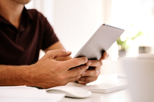Man working on digital tablet sitting at work table
