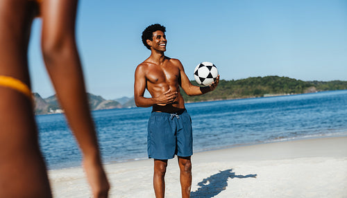 Athletic young man playing with a soccer ball on Praia do Flamengo beach on a sunny day