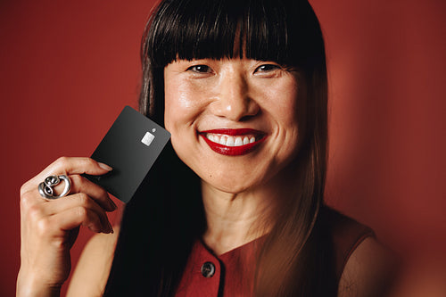 Woman in her 50s holding an exclusive black credit card in her hand