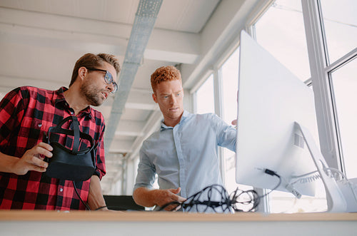 Developers checking test results of virtual reality glasses on computer