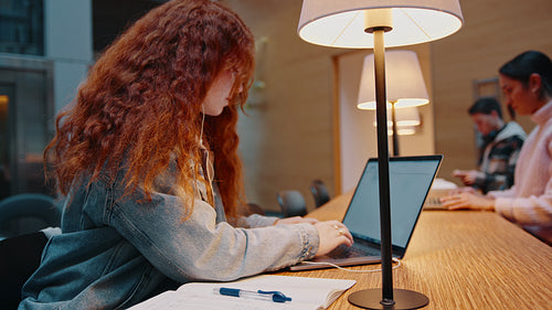 Female college student doing research for an assignment in a university library