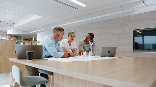 The design of a wind turbine: Engineering team collaborating on a wind energy project in a creative office