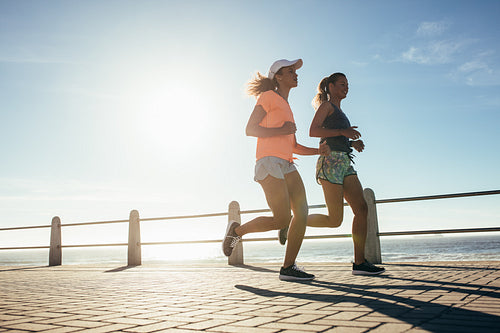 Two young women running on ocean front