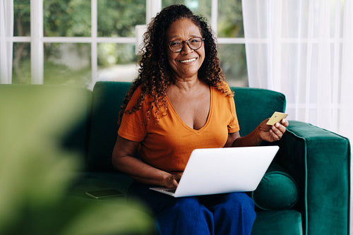 Enjoying retirement with online shopping: Woman using her gold credit card for ecommerce