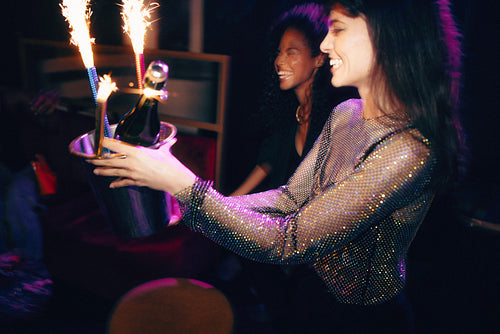 Women celebrating with sparklers and champagne at a vibrant night out