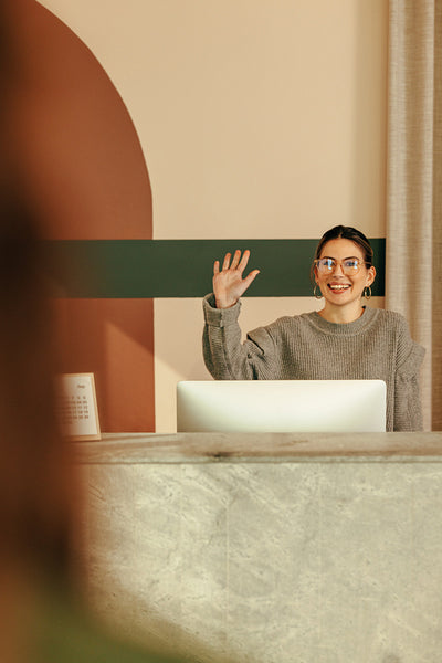 Cheerful female receptionist greeting  a client at the front des