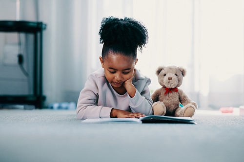 Elementary age child reading a book in her bedroom