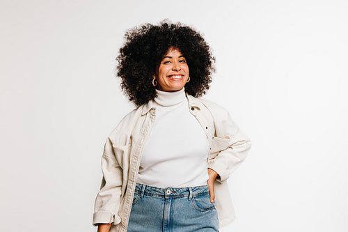 Carefree woman with curly hair smiling at the camera in a studio