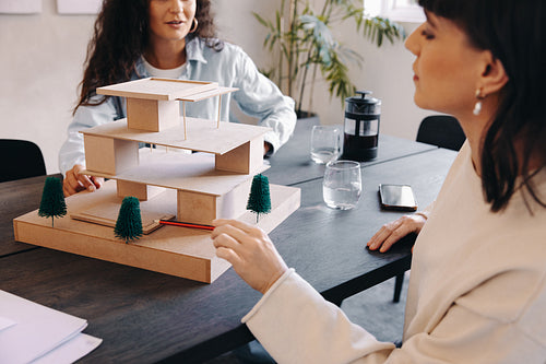 Two professionals discussing a model project during a creative meeting