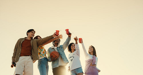 Cheering friends having a fun outdoor gathering, holding drinks and smiling