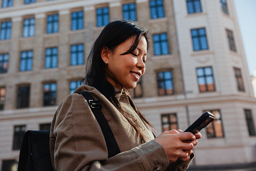 Young woman smiling with smartphone in city