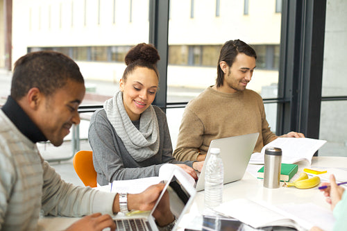 Young students studying in university library with books and laptop