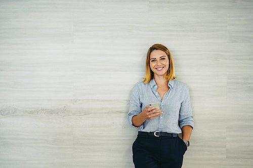 Happy young businesswoman using a smartphone in an office
