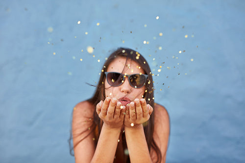 Beautiful woman blowing a burst of magic glitter 