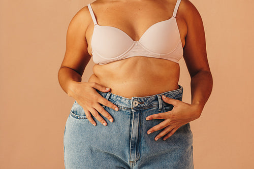 Unrecognizable curvy woman wearing a bra and jeans
