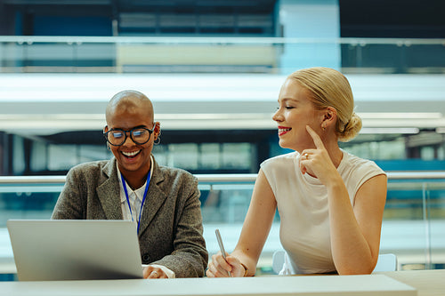 Two female coworkers collaborating at modern corporate office