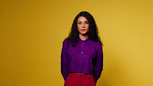 Confident woman poses against a vibrant yellow background
