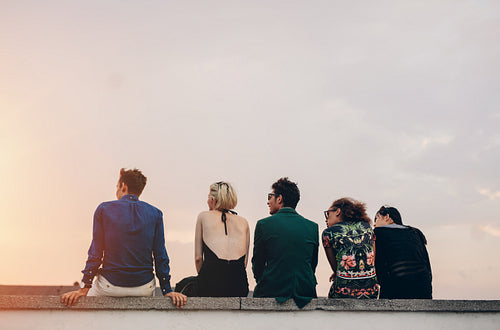 Young people hanging out on rooftop at sunset