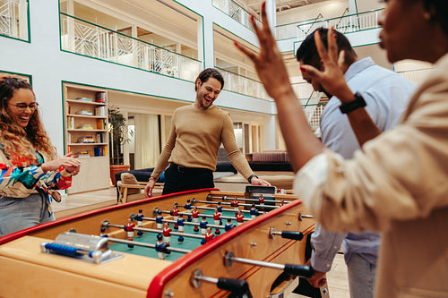 Group of colleagues playing foosball and enjoying a competitive team-building activity
