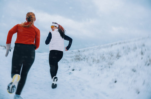 Together, women are running uphill on a snowy winter path