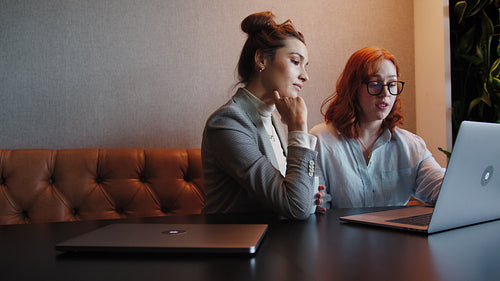 Female professionals having a discussion and working with a laptop