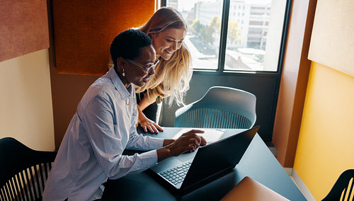 Two women working together on a laptop at a modern office table