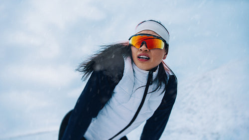 During a cold workout, the woman pauses in winter snow for a short rest