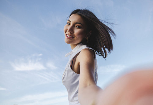Young woman taking a selfie against the sky