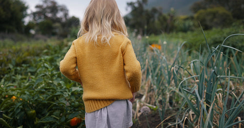 Young girl walking through an organic garden alone