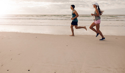 Young couple on running along the shore