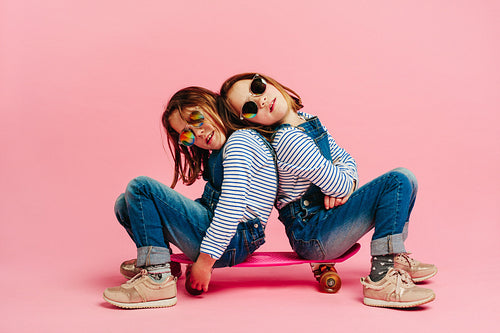 Adorable girls sitting together on a skateboard