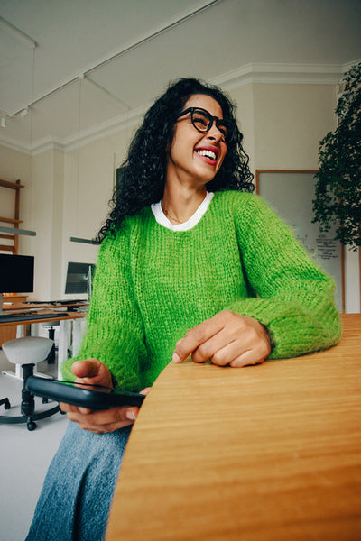The woman brings a laughing mood to a smartphone call at her desk