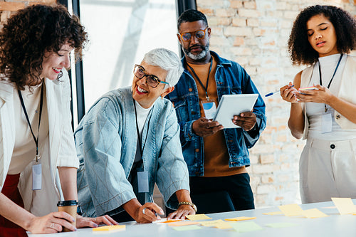 Diverse team using post-it notes and digital tablets for collaborative project planning