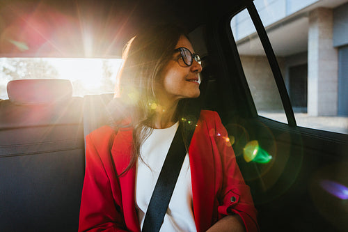 Professional woman smiling in car interior with sun glowing through window