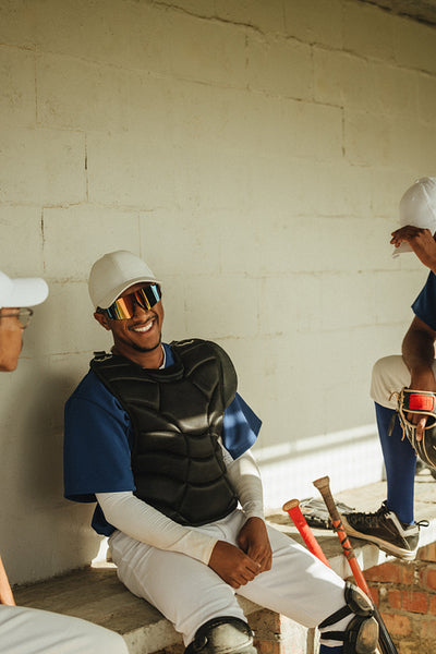 Joyful male baseball player sitting in dugout smiling with passion for the game