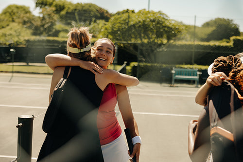 Group of women tennis players hugging and celebrating on court