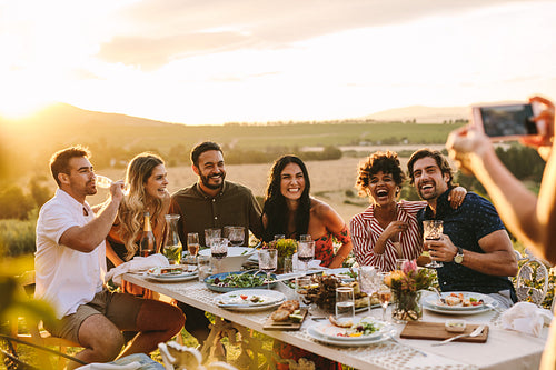 Woman taking picture of her friends at dinner party