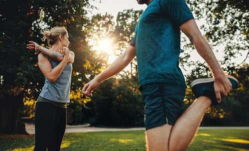 Young couple warming up for morning workout in the park