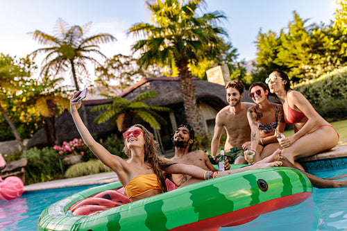 Girl with friends taking selfie at pool party