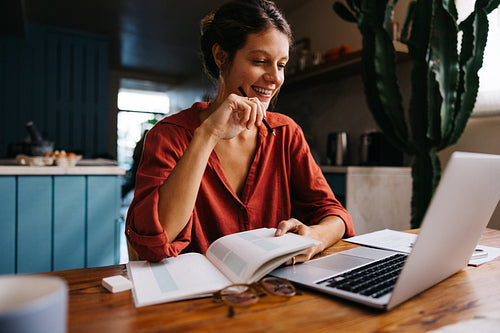 Woman studying at home desk with laptop