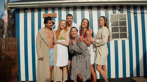 Friends in bathrobe laughing together outside a spa retreat cabin