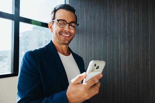 Using smartphone for communication near window in stylish office