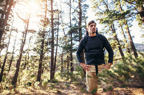 Man standing in forest wearing a backpack