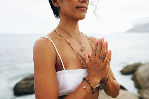 Bohemian woman doing yoga in a prayer pose by the seaside