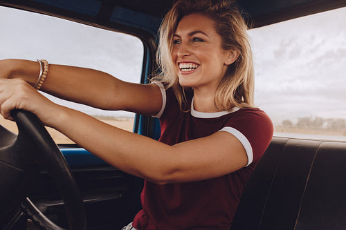 Smiling woman enjoying driving a car on road trip