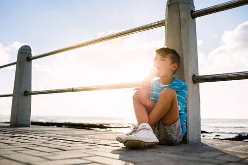 Boy eating an ice cream sitting near seashore